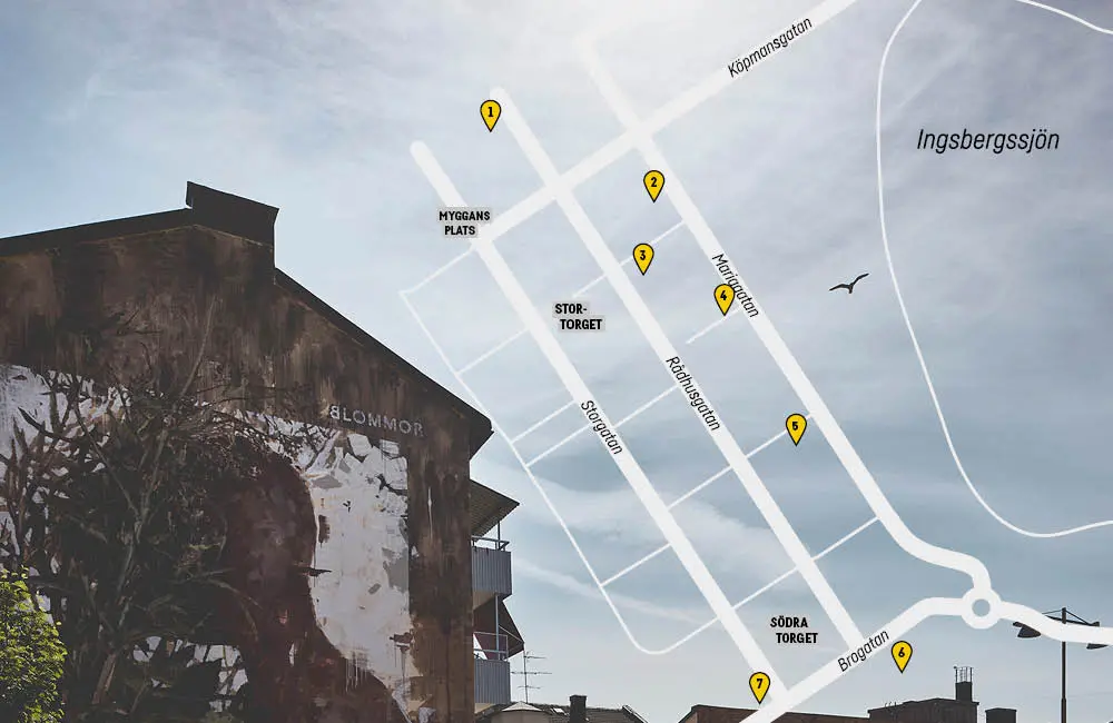 En karta över Nässjö stad som markerar var väggmålningarna är placerade. I bakgrunden syns en husvägg med en målning på och en himmel.